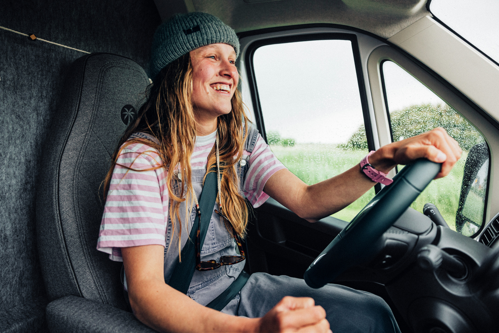 A traveler wearing a seat belt at the wheel of a campervan